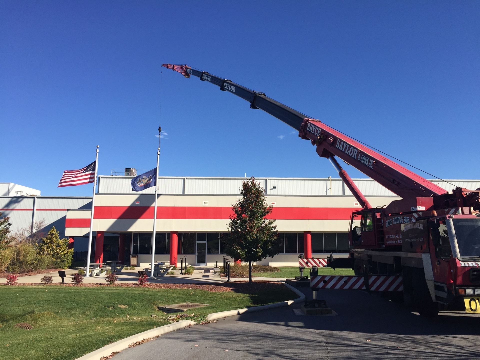 Fire truck with raised ladder outside a building, with American flags flying in front.