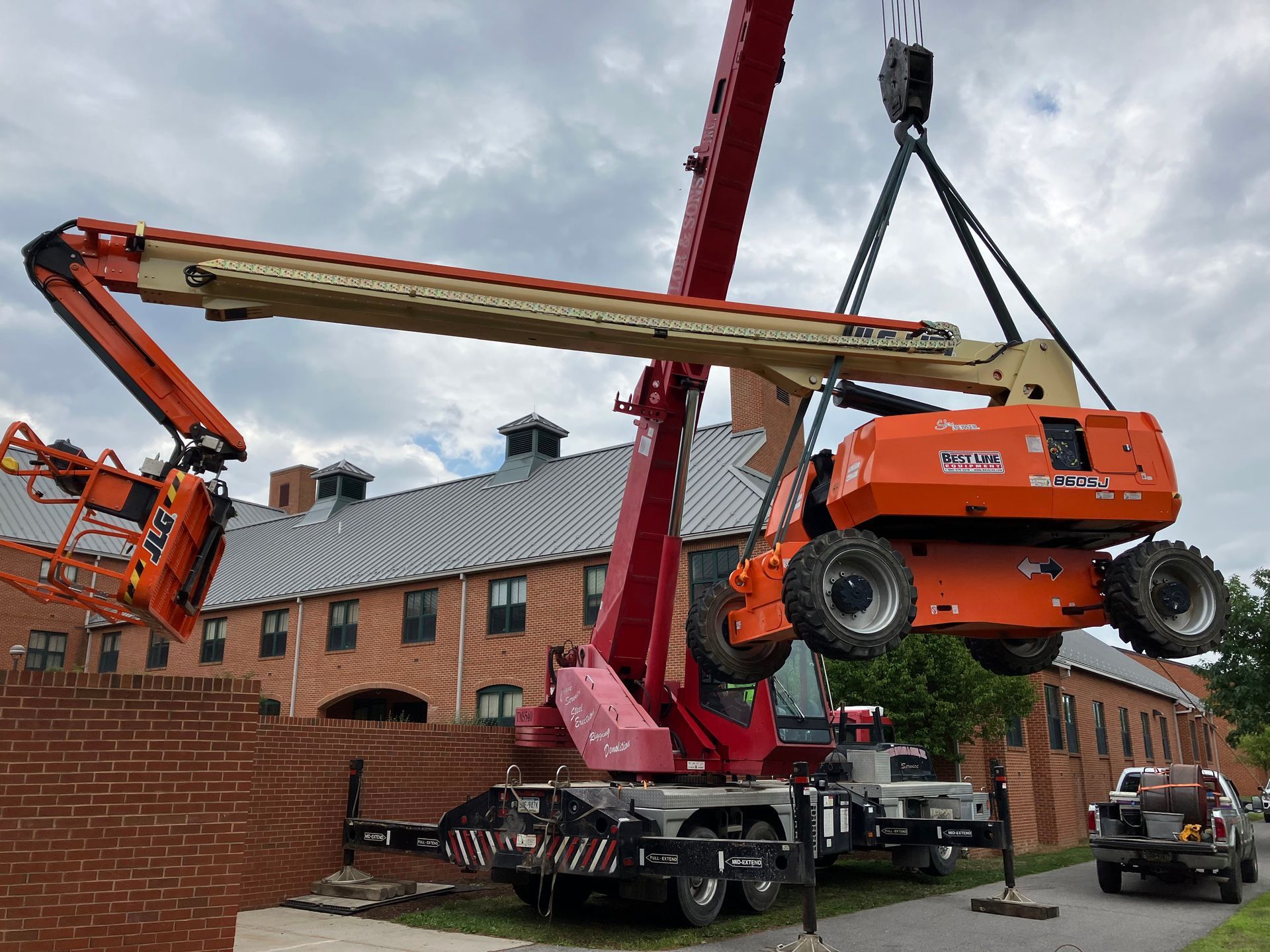 Crane lifting a cherry picker beside a brick building during storm damage repair