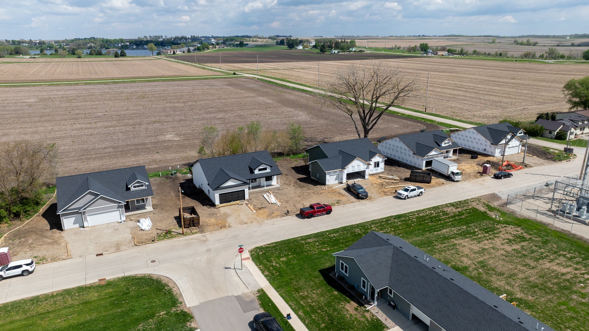 Aerial view of suburban homes along a street beside open farmland on a sunny day
