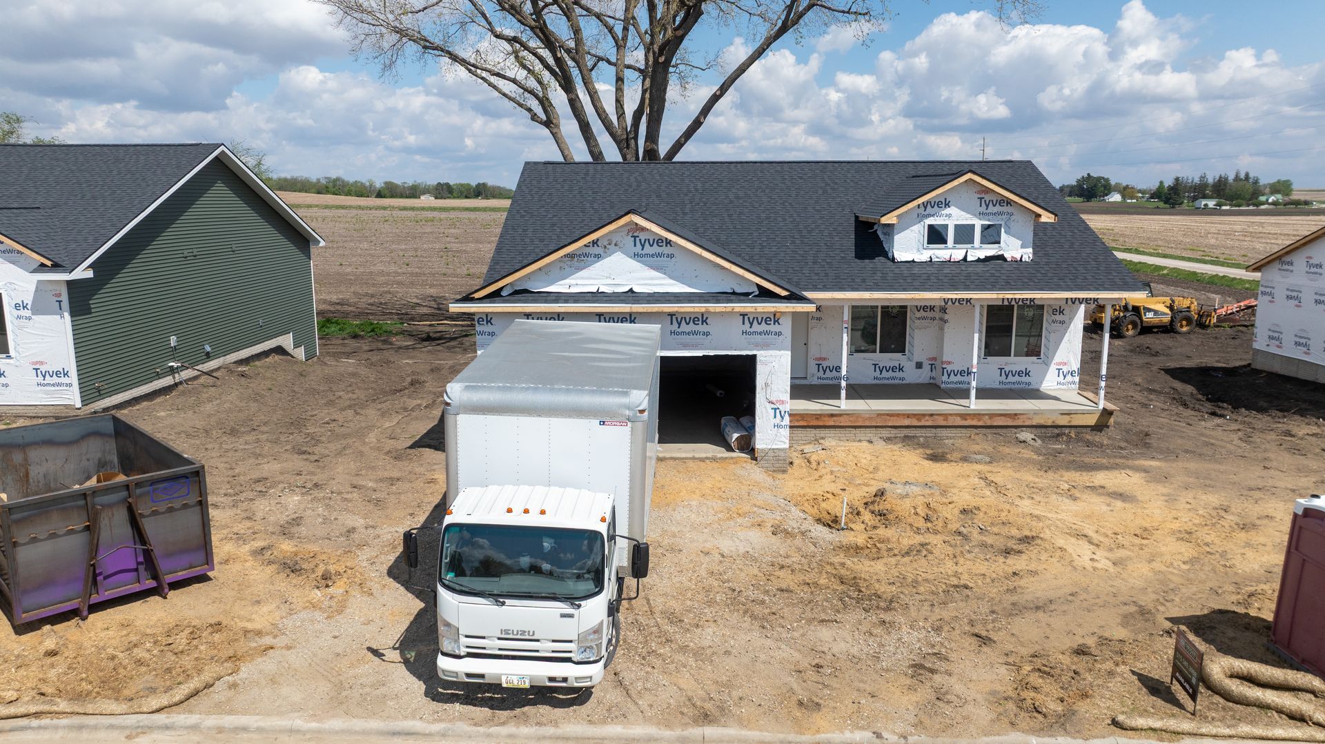 House under construction with a white truck in front and a newly built garage in a rural lot.