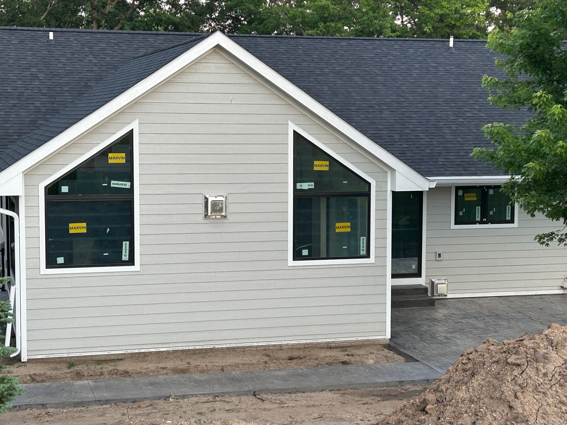Front view of a gray house under construction with black roof and large windows