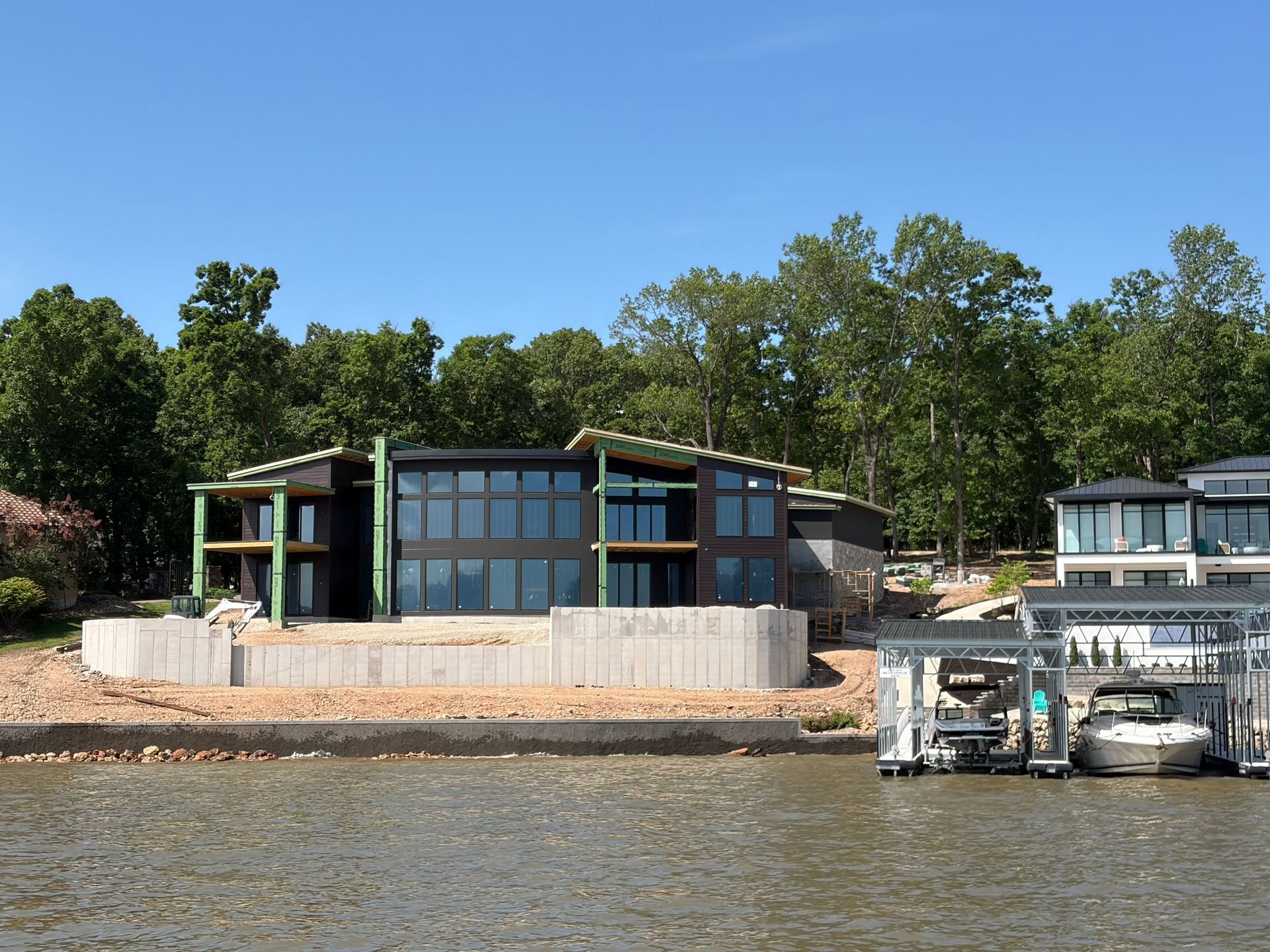 Modern lakeside house with large windows and docked boats on calm water