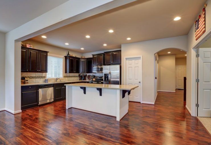 Kitchen with dark cabinets, white island, and hardwood floors.