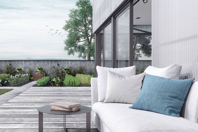 Outdoor patio with white couch, pillows, small table, and garden.