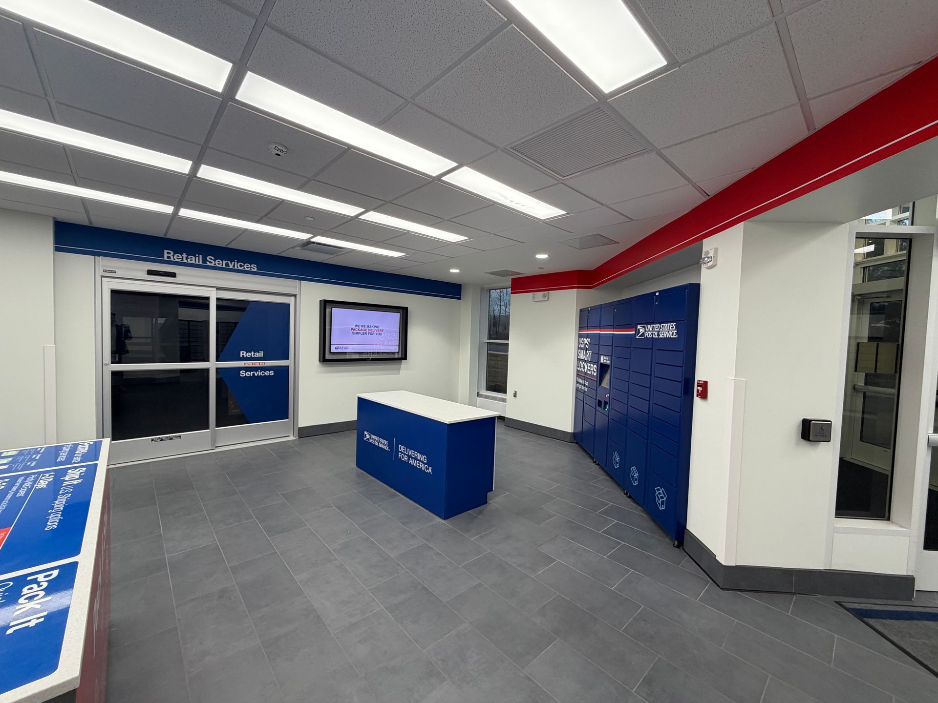 Interior of a blue and white retail space with a blue locker system, and a digital display.