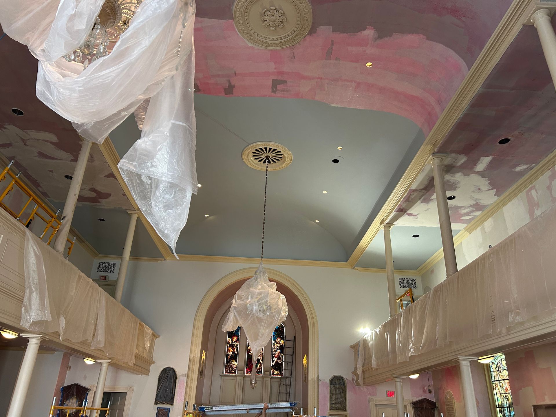 Interior of a church undergoing renovation, with scaffolding, plastic sheeting, and exposed ceiling.