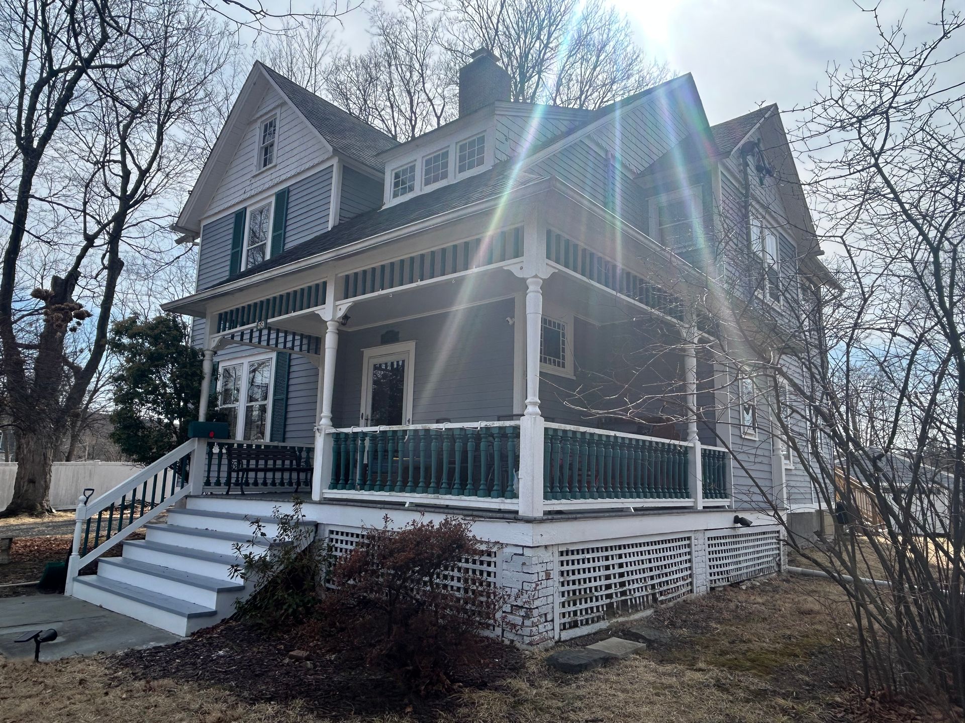 Two-story Victorian house with gray siding, white trim, and a wraparound porch.