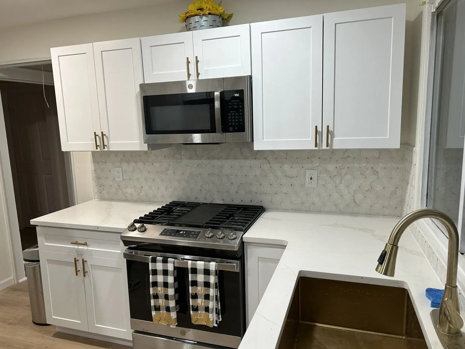White kitchen with stainless steel appliances, white cabinets, and white countertops.