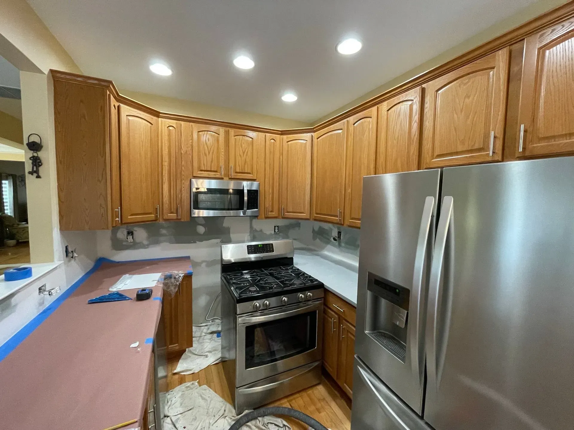 Kitchen under renovation with oak cabinets, stainless steel appliances, and exposed backsplash.