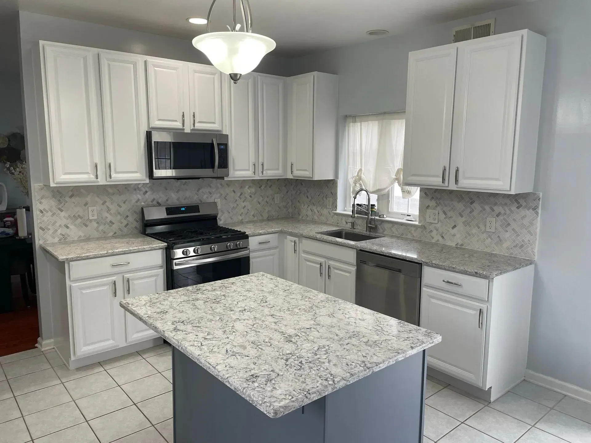 White kitchen with stainless steel appliances, granite countertops, and a gray island.