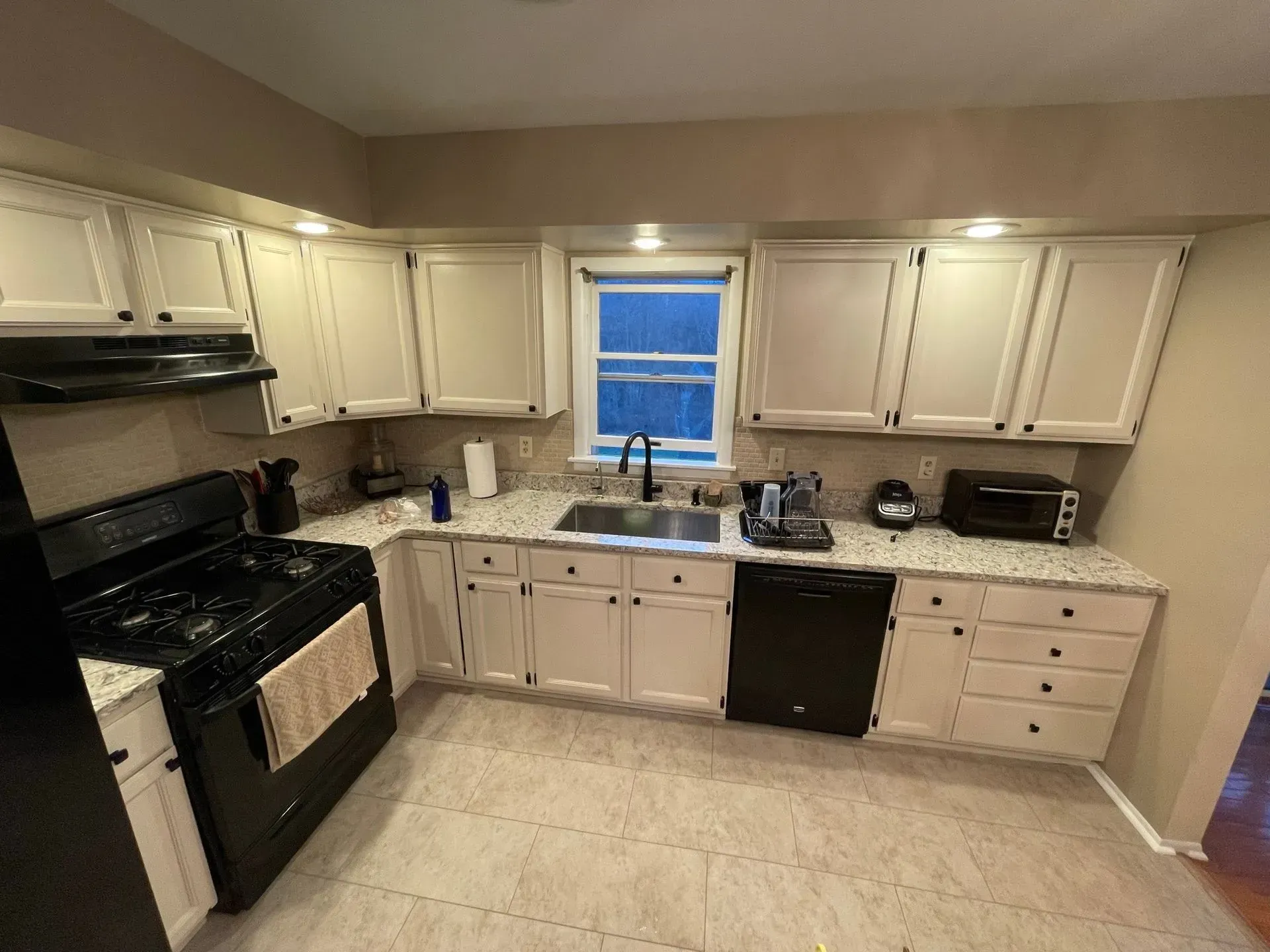 Kitchen with white cabinets, black appliances, and granite countertops.