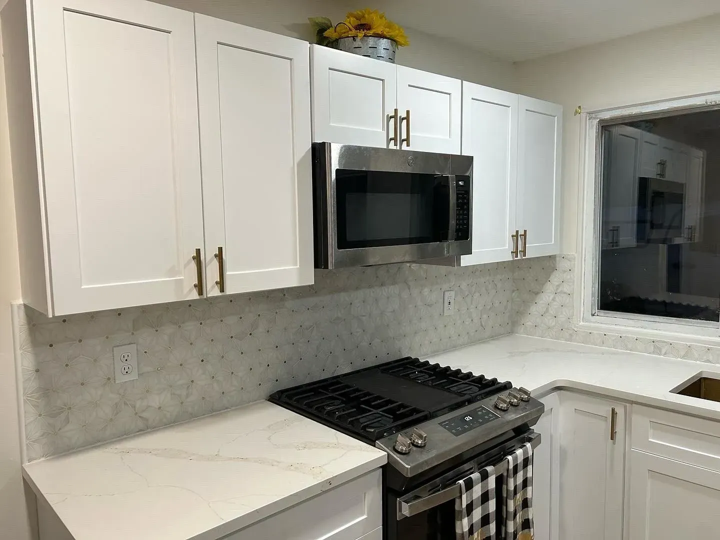 White kitchen with quartz countertops and stainless steel appliances.
