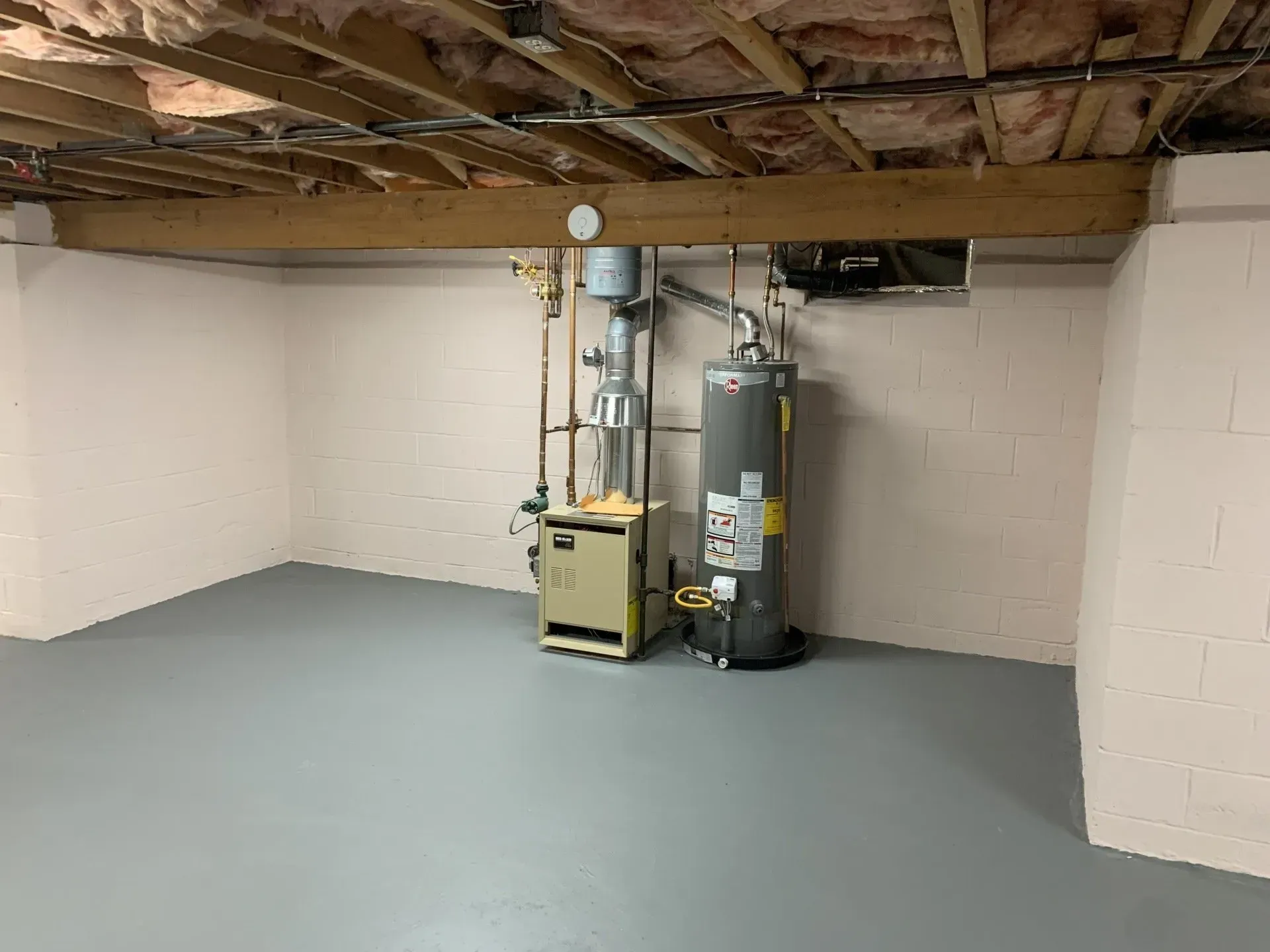 Basement room with water heater, furnace, and exposed ceiling. Gray floor, white walls.