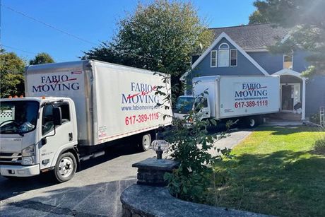 Two moving trucks are parked in front of a house.