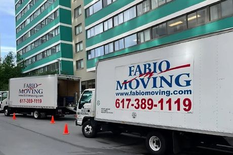 Two moving trucks are parked in front of a building.