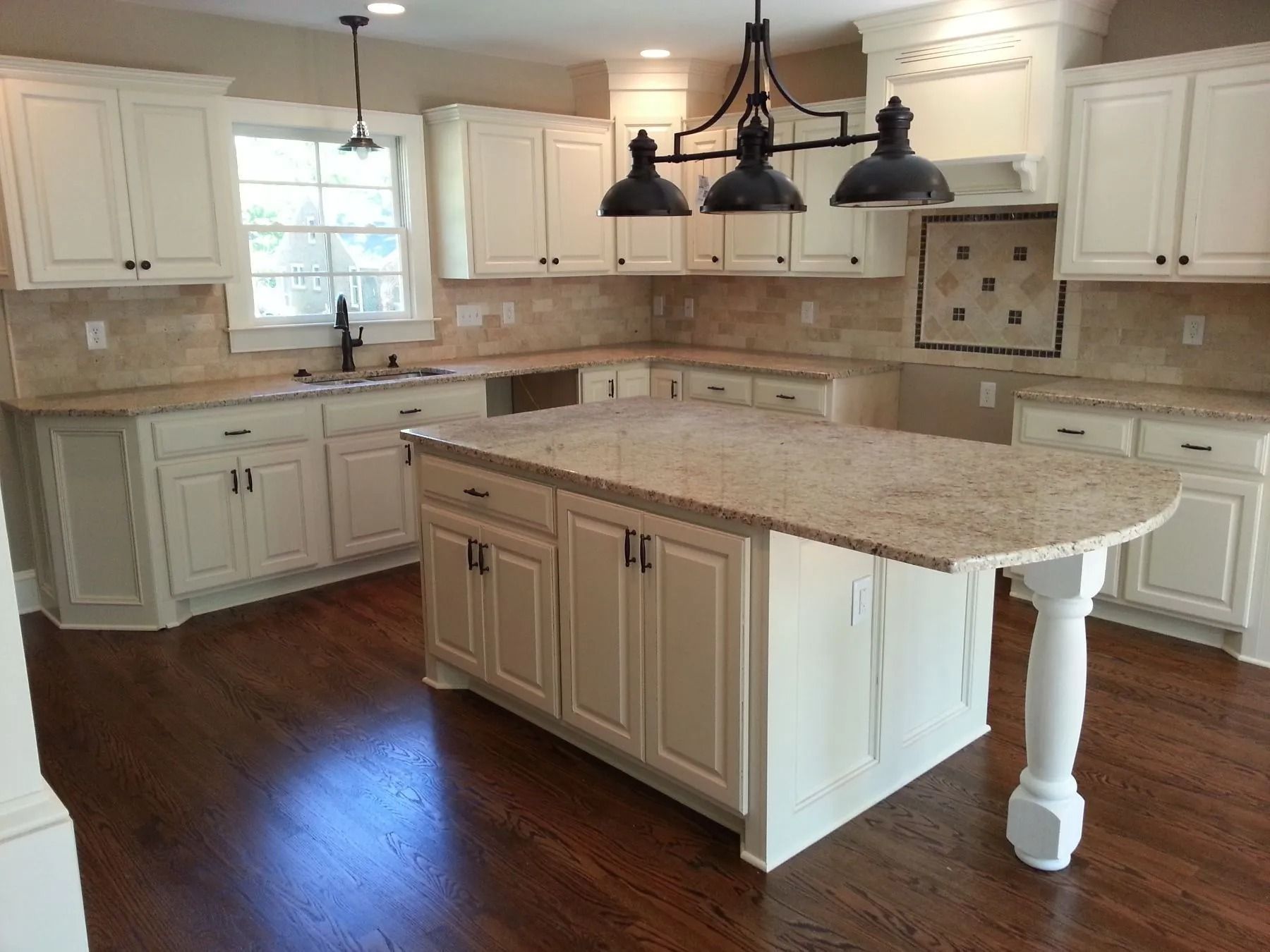 A kitchen with white cabinets and a large island in the middle