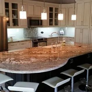 A kitchen with a large granite counter top and stools.