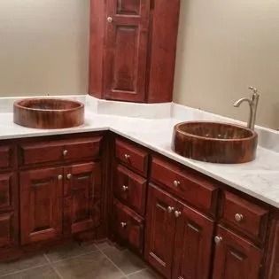 There are two sinks in the bathroom with wooden cabinets.