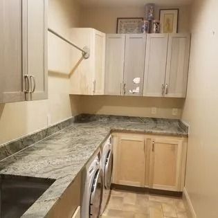 A laundry room with a washer and dryer , granite counter tops , cabinets and a sink.