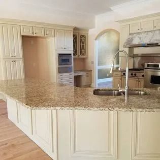 A kitchen with white cabinets , granite counter tops , a sink , and a stove.