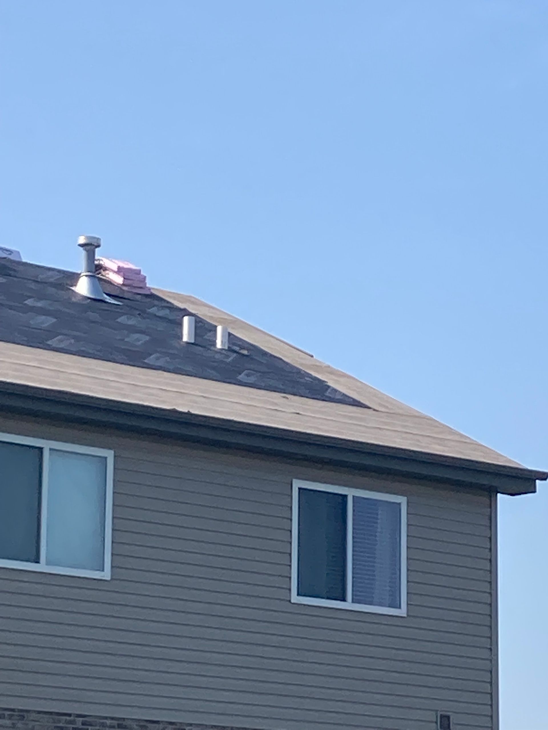 House exterior with roof, windows, and clear blue sky.