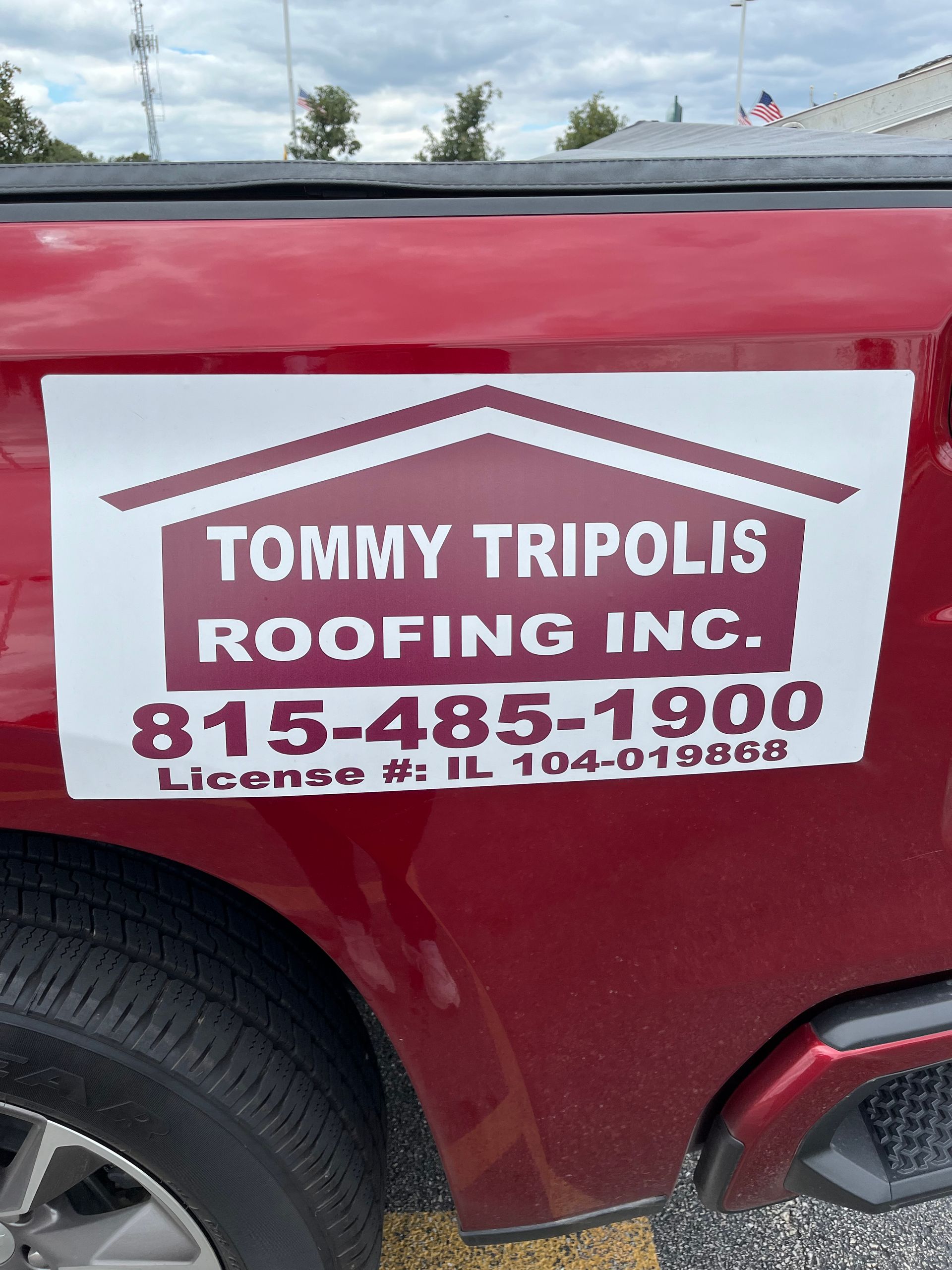A red truck with a white and maroon magnetic sign that reads 
