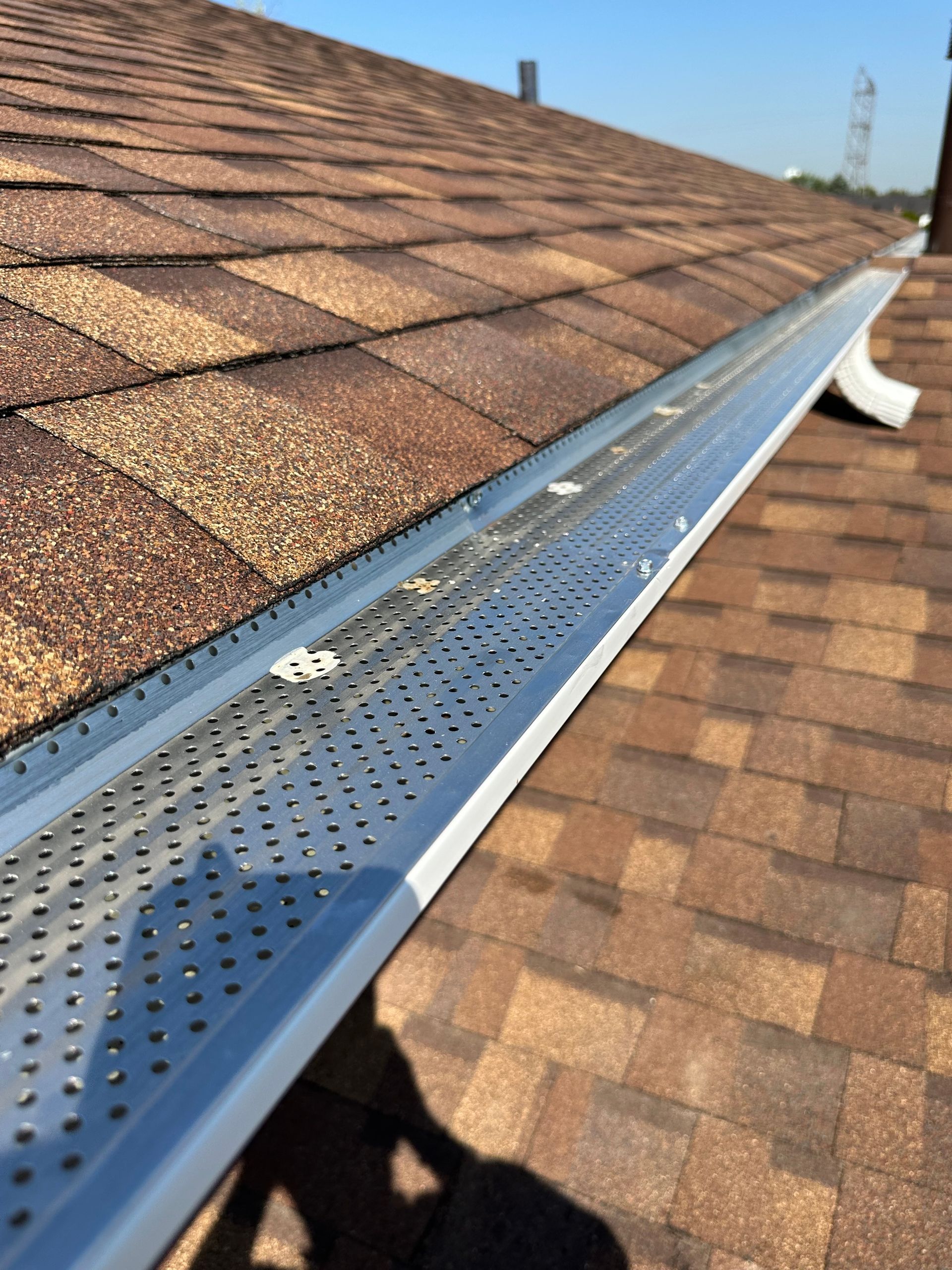 Brown shingle roof with silver gutter guard, angled shot.