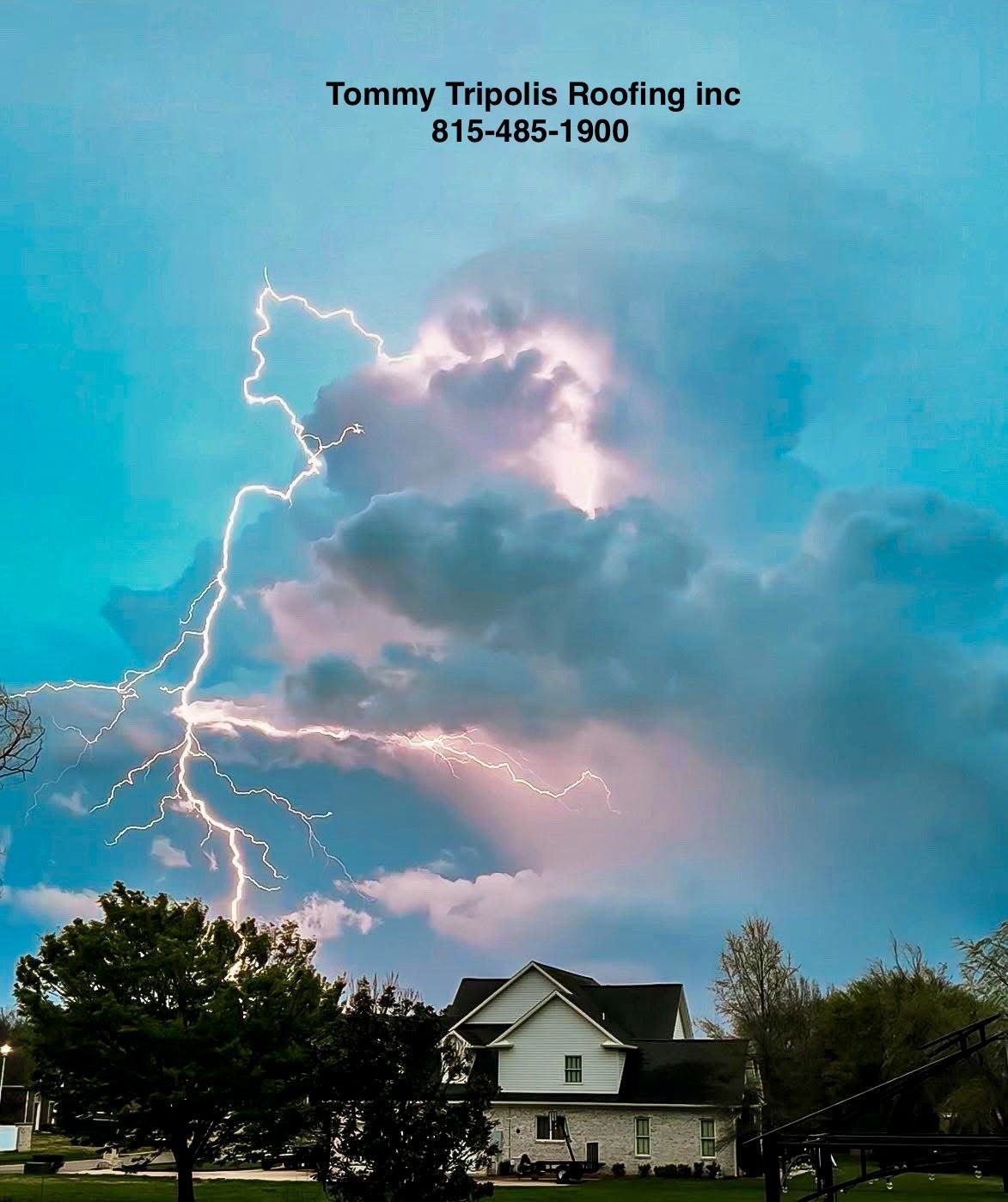 Lightning strikes behind a house during a storm with cloudy sky.