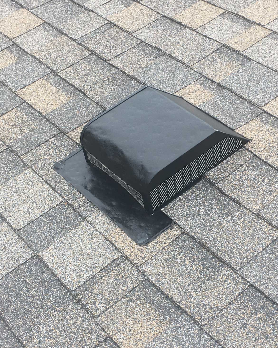 Black roof vent on gray asphalt shingles.