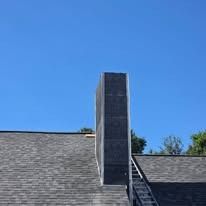 Chimney on a roof against a clear blue sky.