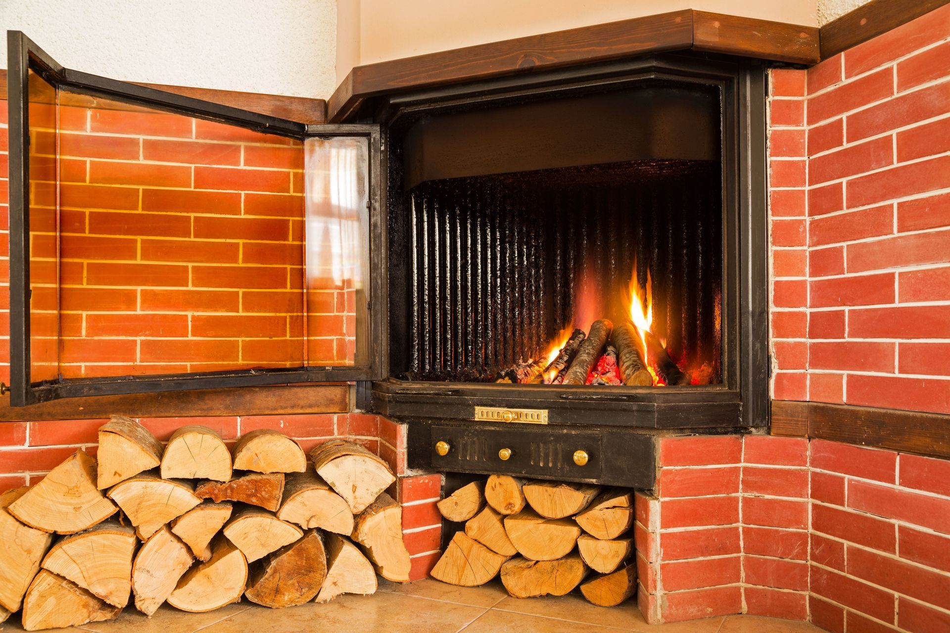 Fireplace with burning wood, brick surround, and stacked firewood.