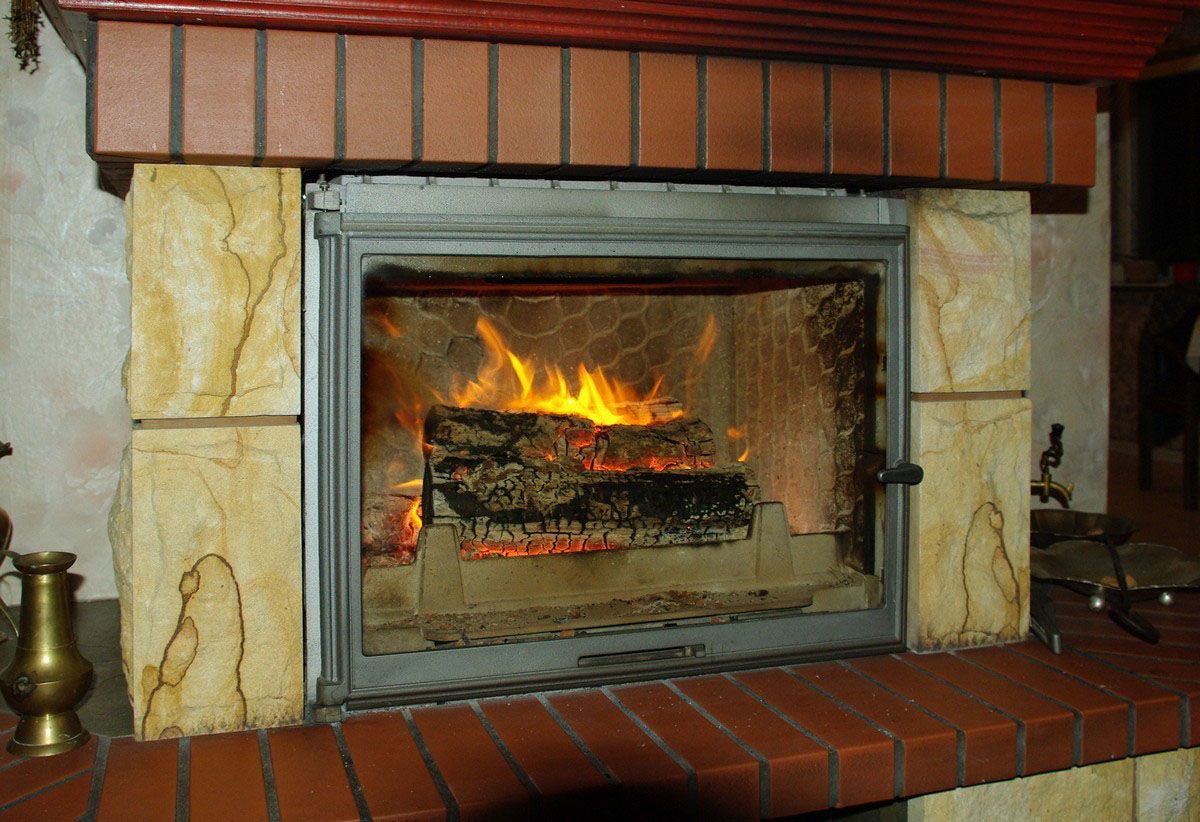 Fireplace with burning logs, inside brick and stone surround.