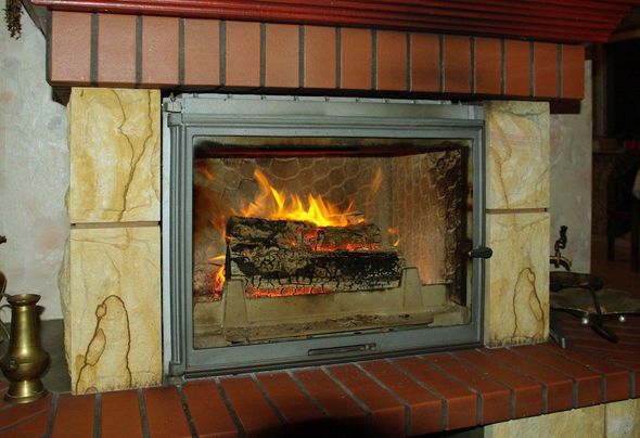 Fireplace with burning logs, inside brick and stone surround.
