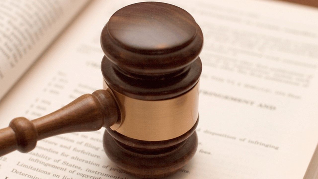 A wooden judge 's gavel is sitting on top of an open book