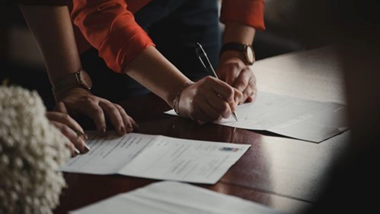 A group of people are sitting at a table signing papers.