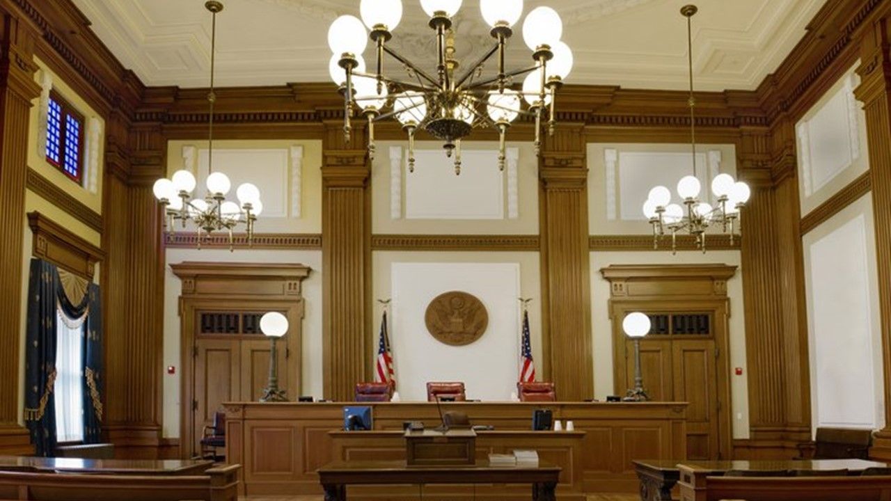 An empty courtroom with a chandelier hanging from the ceiling