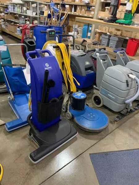 Assortment of floor cleaning machines in a store, featuring blue, gray, and yellow models.