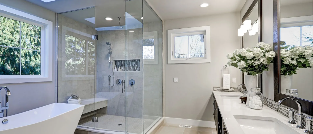 Bathroom with a glass shower, soaking tub, vanity with a mirror, and flowers on the countertop.