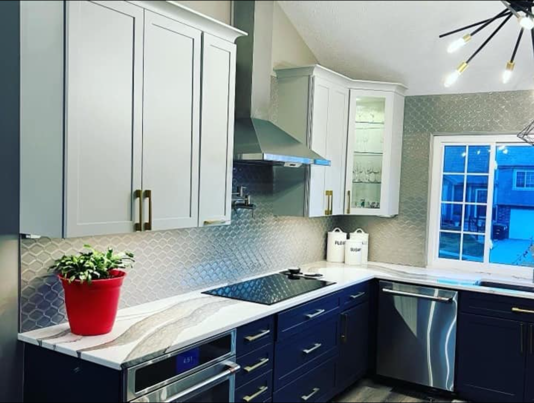 Modern kitchen with blue and white cabinets, stainless steel appliances, and a tiled backsplash.
