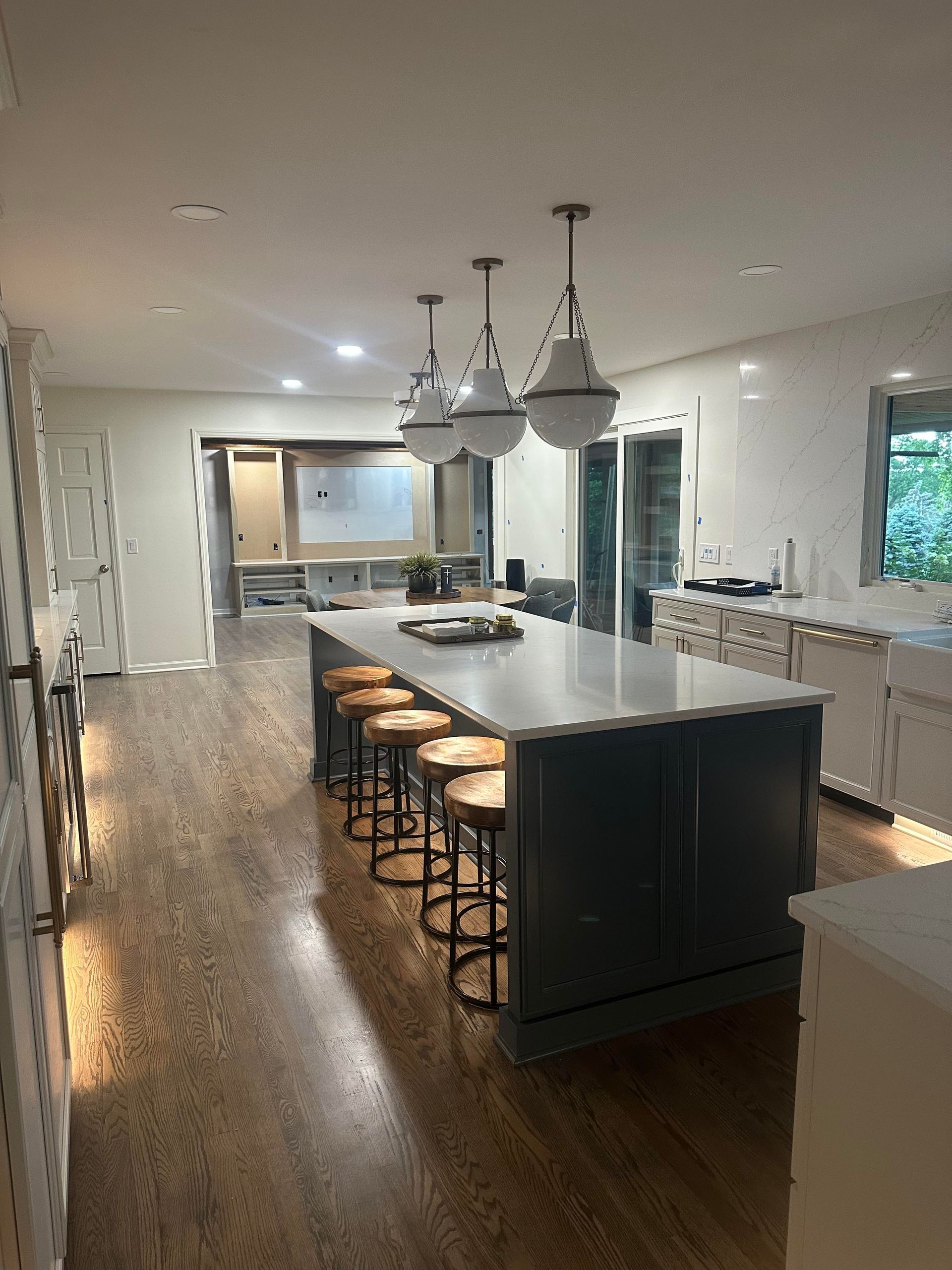 Kitchen with blue island, white countertops, pendant lights, and wooden floors.