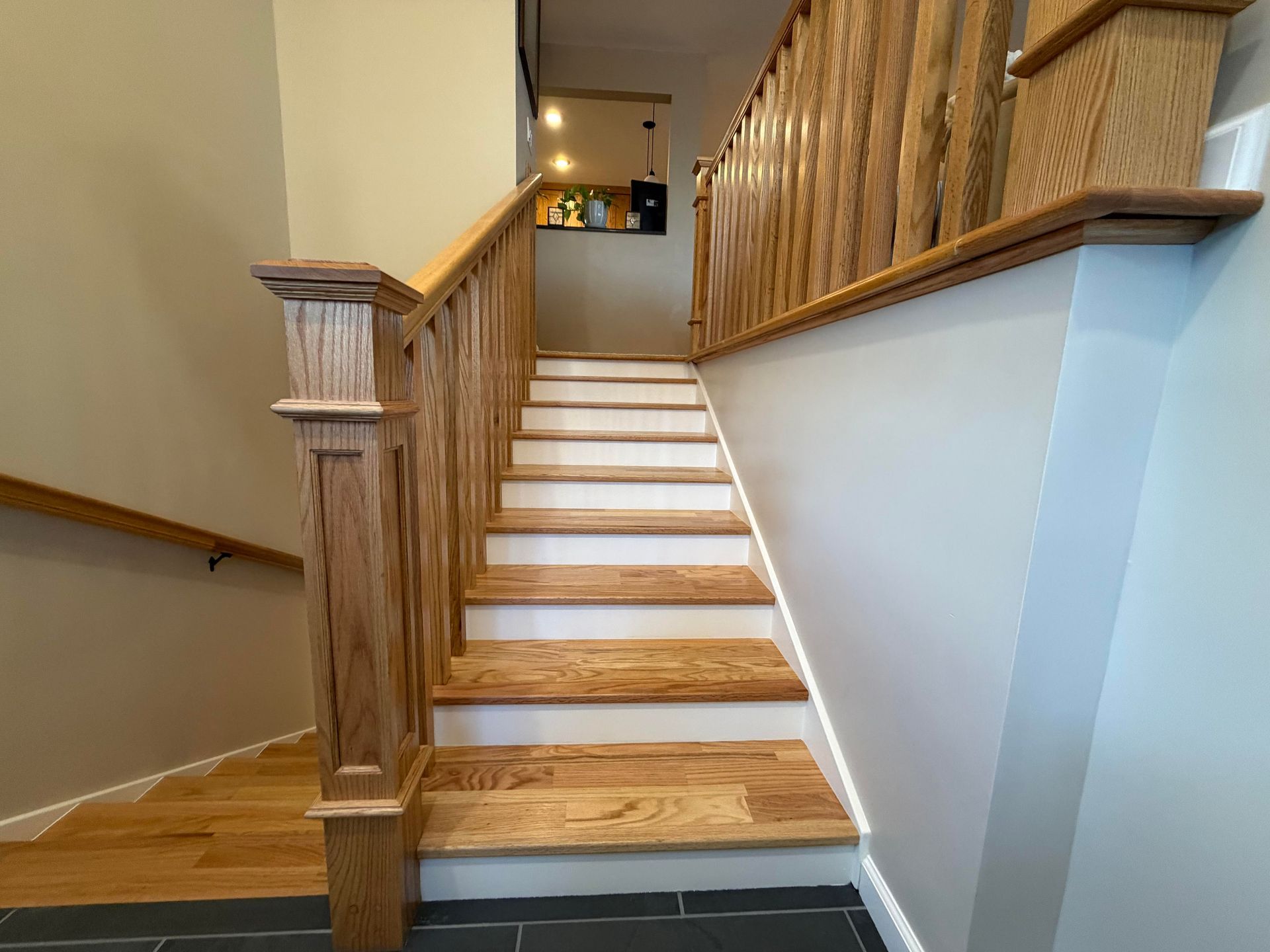 Wooden staircase with oak banisters and handrails, leading upwards.