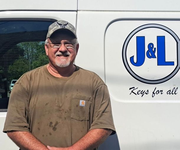 Man in work clothes smiles next to a white van with "J & L Keys for all" logo.