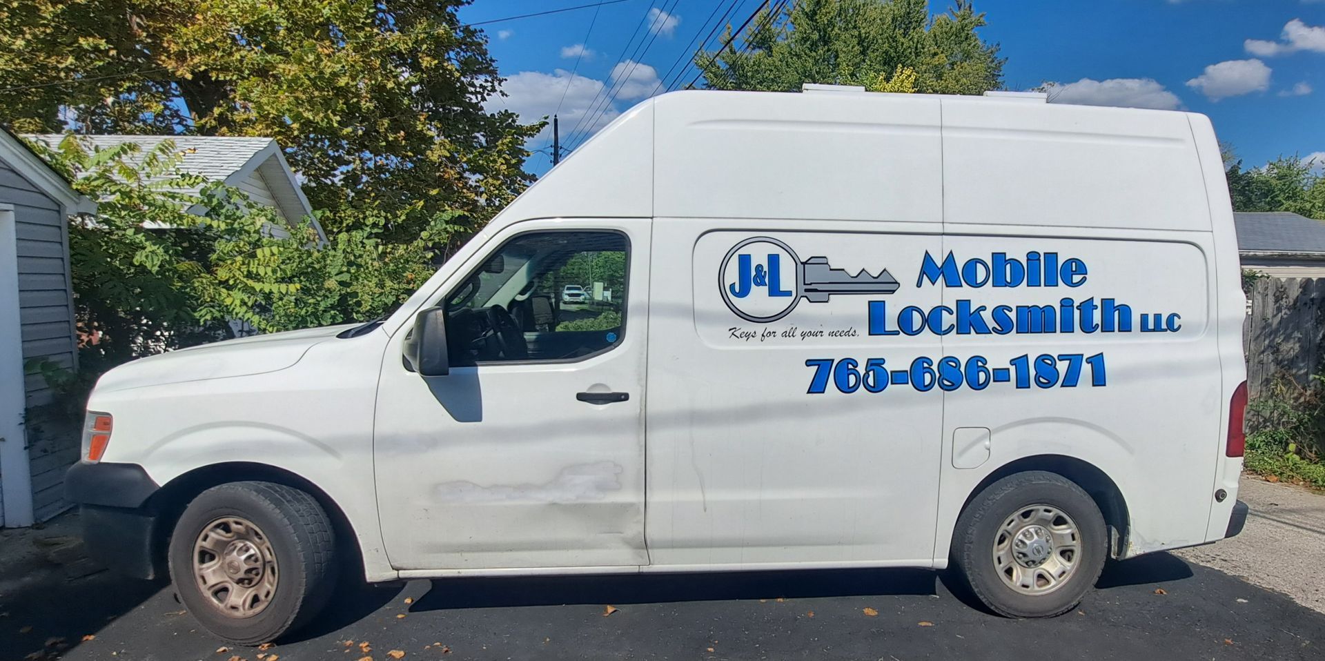 White locksmith van with blue text, parked on a street.