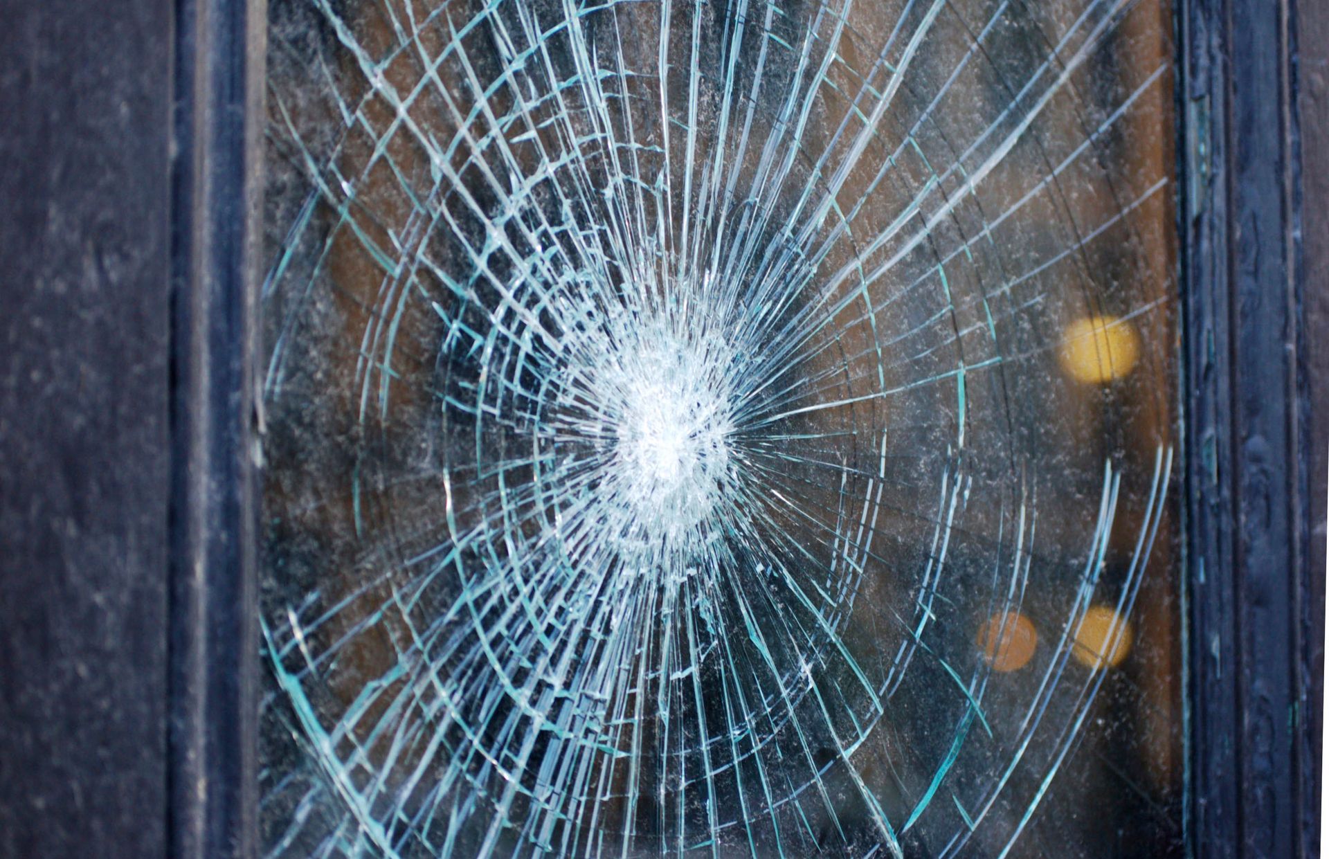 Shattered glass windowpane with radiating cracks.