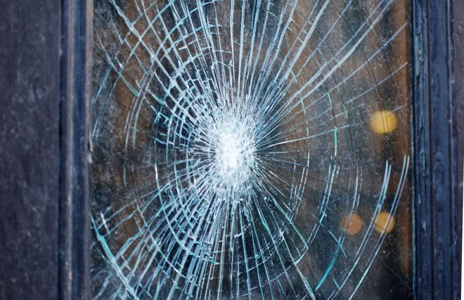 Shattered glass windowpane with radiating cracks.