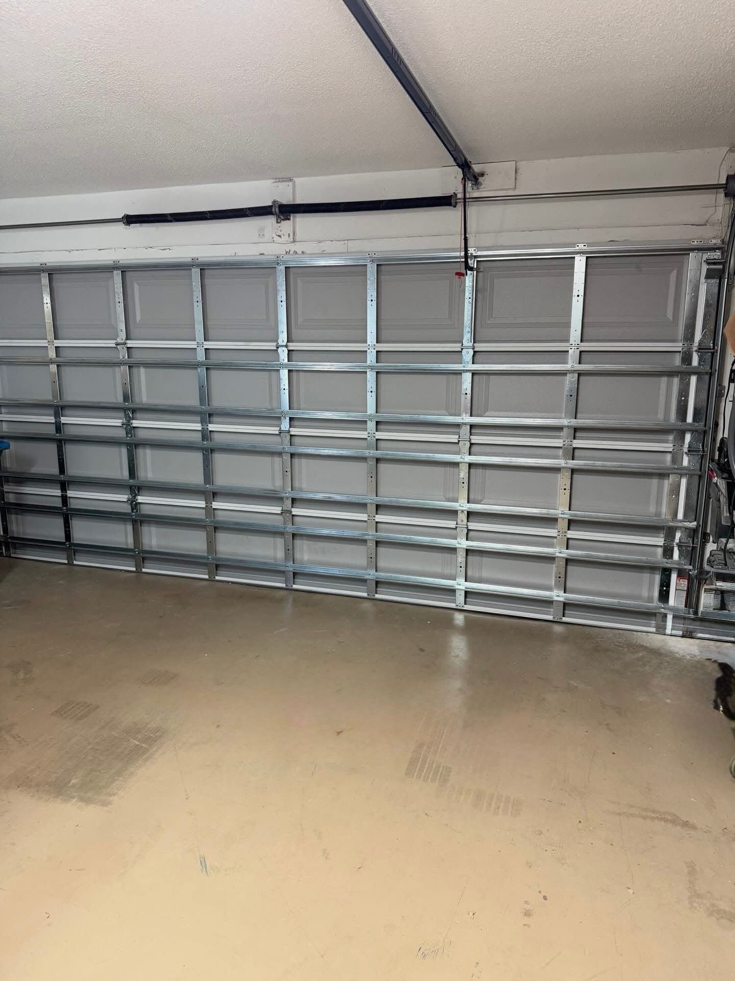 Interior of a garage with a metal frame garage door. The floor is light brown.