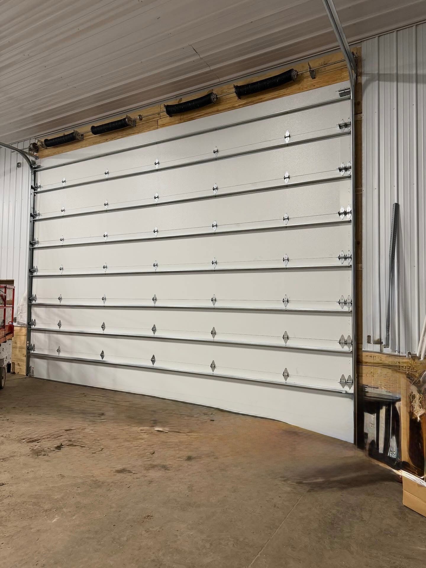 White industrial garage door, closed, in a workshop setting.
