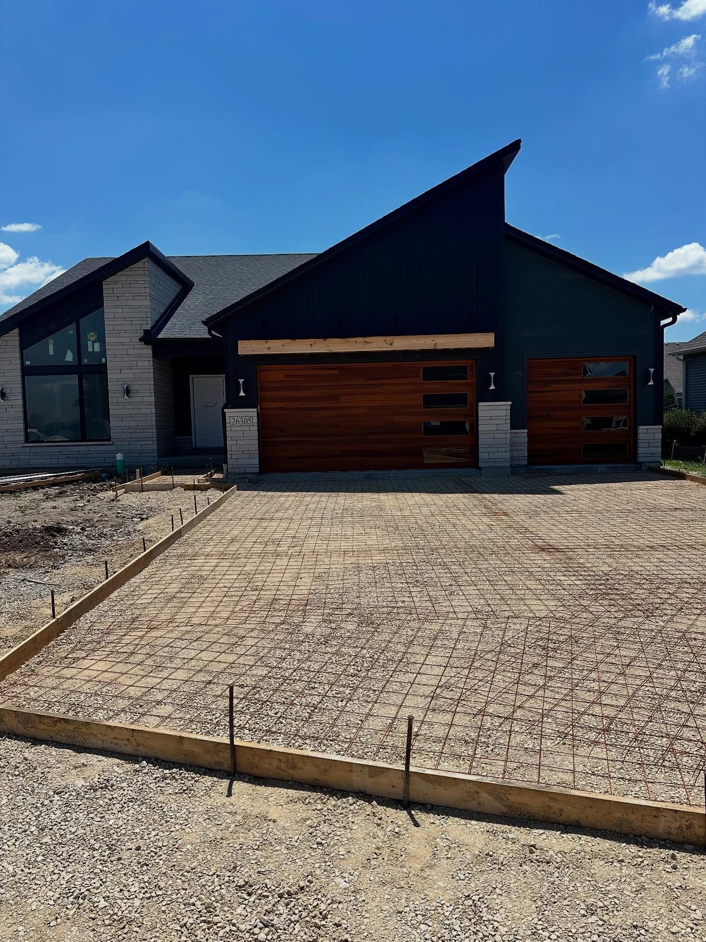 New house under construction with brown garage doors and a concrete driveway.