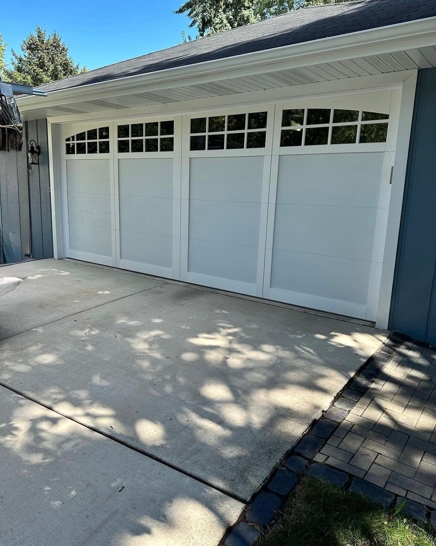 White garage door with glass panes above; concrete driveway.