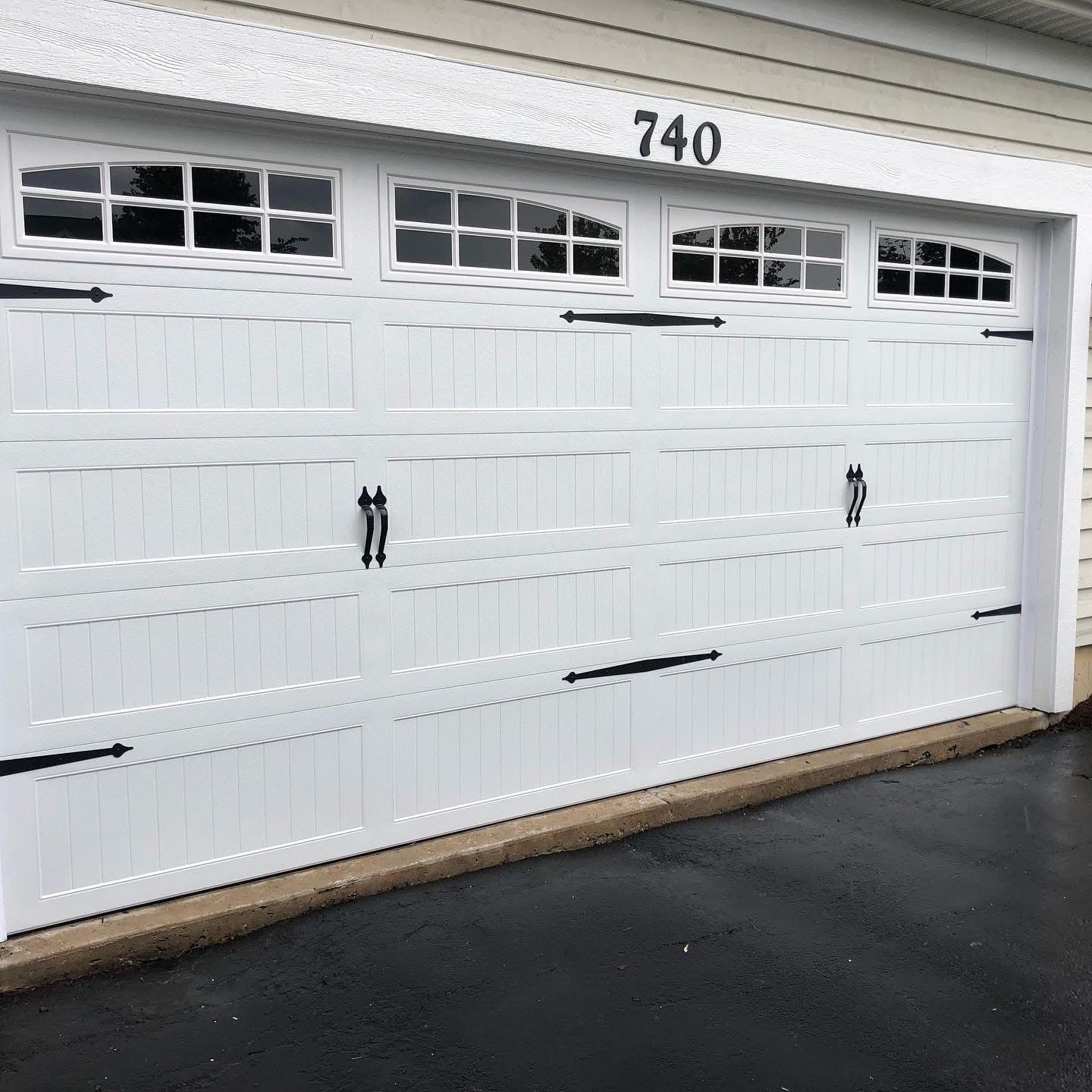 White garage door with decorative black hardware and windows. Number 